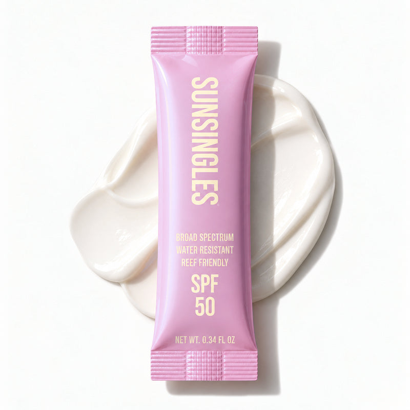 Pink SunSingles single-use SPF 50 sunscreen packet, 0.34 fl oz, on a swatch of sunscreen